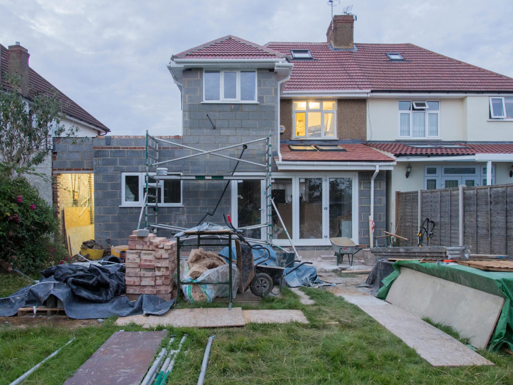 A suburban house undergoing major renovations with scaffolding and building materials.